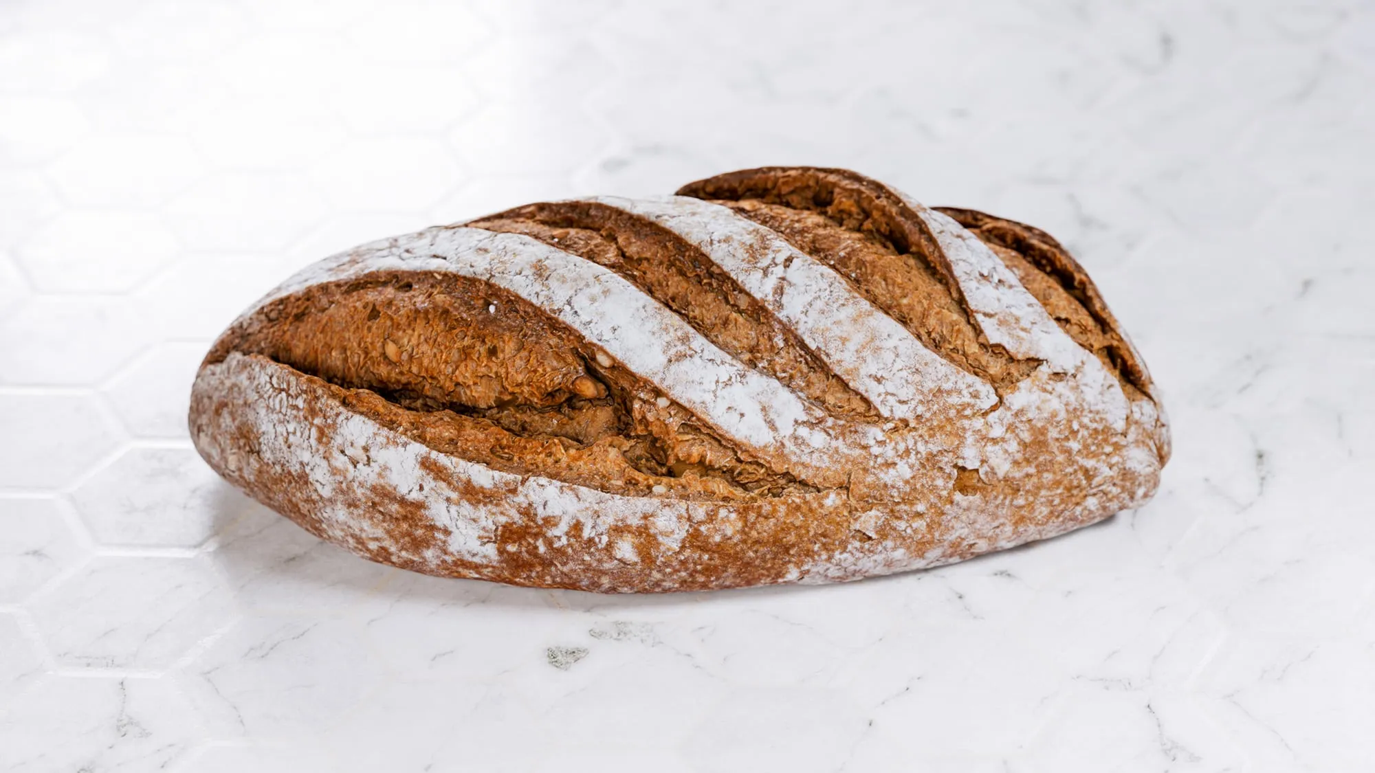 Side view of a loaf of bread on tiled white background