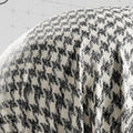 Close-up of a textured fabric with a houndstooth pattern on a white background.